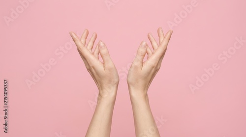 Two hands reaching upwards against a pink background
