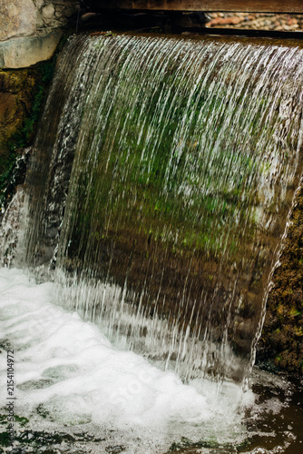A small decorative waterfall in the city park. Clean, refreshing water.