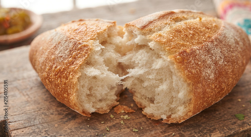 A hyper-realistic macro photograph focusing on the golden, crackly crust of a freshly baked bolillo roll, showing the contrast between the crisp exterior and the soft, fluffy crumb inside.
