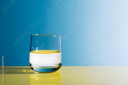 A Captivating Still Life: Glass Filled with Yellow and White Liquids on a Vibrant Blue and Yellow Background