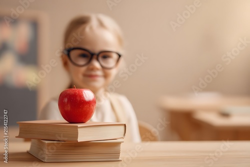 A Young Student with Glasses, an Apple on Textbooks, Embodying the Spirit of Learning and Curiosity in a Classroom Environment