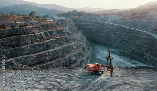 Open Pit Quarry with Rock Drilling Machine and Terraced Mine Landscape