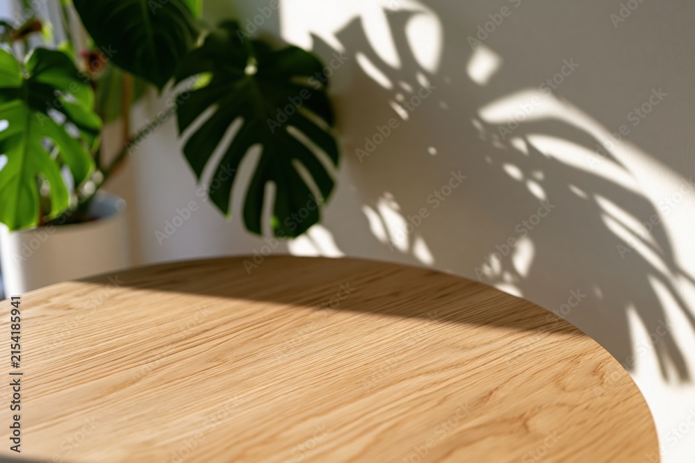 Fototapeta premium The Wooden Table in Sunlit Corner with Plant Shadows and Warm Natural Light