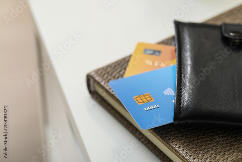 Fotografie Credit cards in a black leather wallet on a textured notebook, financial managem