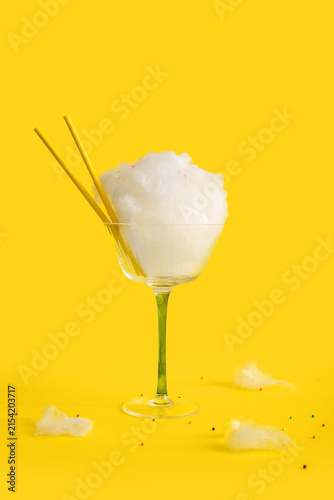 Konstfotografi Glass with sweet cotton candy, straws and sprinkles on yellow background