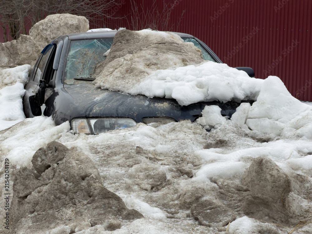 Obraz premium Snow-covered car stuck in deep snow pile. Frozen landscape shows harsh winter weather.