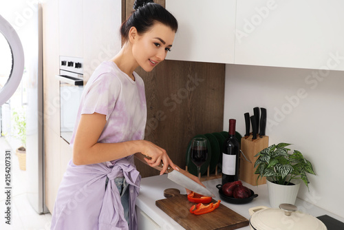 Young woman cutting bell pepper while recording cooking video class in kitchen