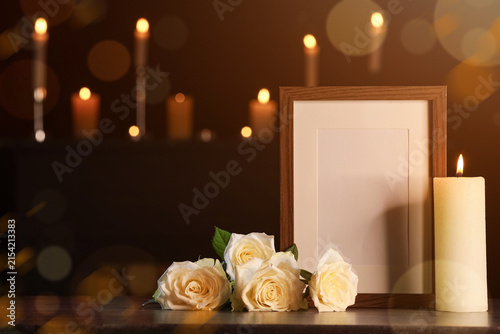 Fotografía Empty wooden photo frame with white roses and burning candles for memorial servi