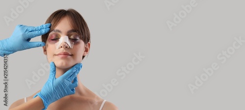 Bild auf Leinwand Young woman with bruised eyes and bandaged nose after rhinoplasty surgery, docto