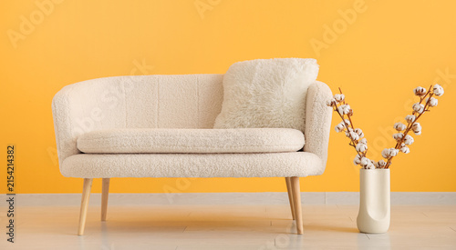 Obraz na plátně Cozy cream boucle sofa with a fluffy pillow and cotton branches in a vase agains