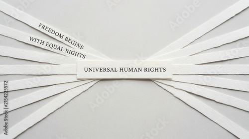 Universal Human Rights concept message displayed on white paper strips over a neutral grey background representing freedom and equality for all people globally in a clean minimalist design