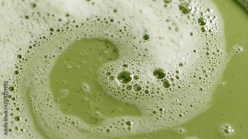Pouring green liquid creating bubbles and foam