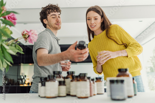 Young man and woman compare health supplements at home
