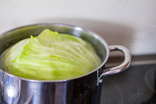 Cabbage leaves boil in a pot while preparing homemade cabbage rolls. Concept of cooking process, practical kitchen skills and family recipe passed to next generation