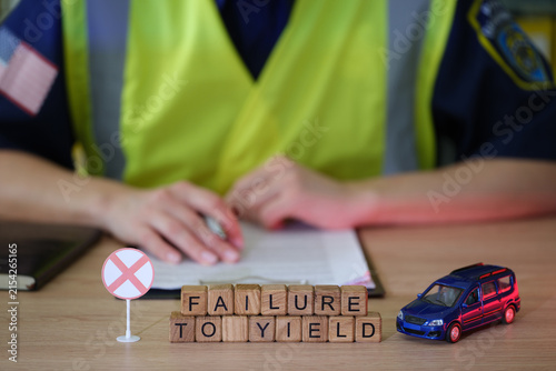 Foto On a sunny day in a bustling town, a traffic officer reviews notes while colorful blocks spell Failure to Yield