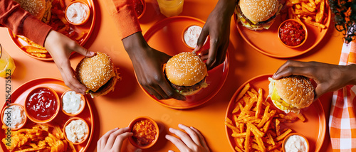 Vibrant overhead shot of diverse hands reaching for juicy burgers on retro orange trays perfect for fast casual dining campaigns, food delivery apps, and social dining concepts.