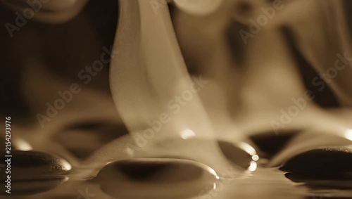 Macro smooth black stones in steaming spa water.