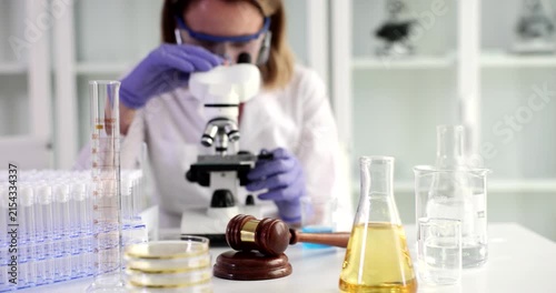 In a vibrant laboratory setting, a researcher carefully examines samples using a microscope. Various colorful liquids and glassware surround her as she explores the intricate details of her work.