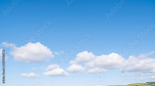 Quadro su tela Bright blue sky with fluffy white cumulus clouds, showcasing a serene and expansive natural landscape scene in daylight