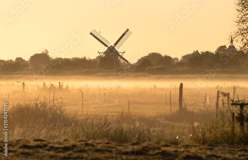 A windmill on a foggy, summers morning in the Dutch countryside.