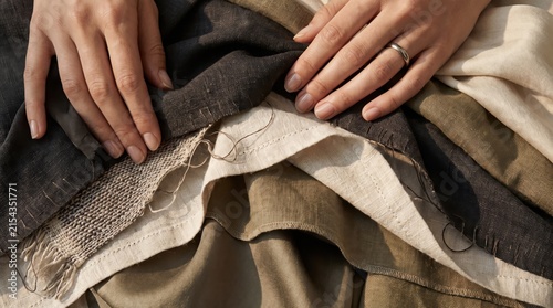 Hands touching textured linen and cotton fabrics in neutral organic tones close up