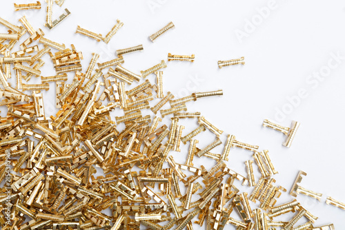 Fotografie Scattered brass electrical components on white surface