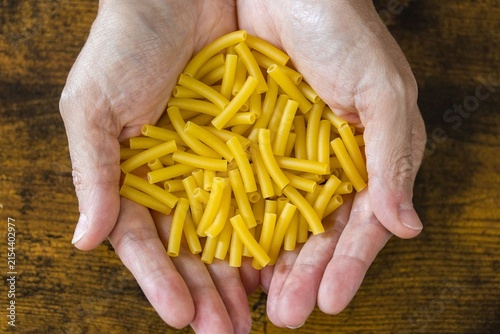 Mains présentant des pâtes macaronis crues
