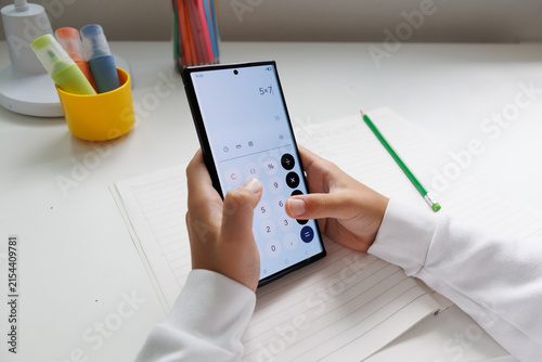 Foto Child calculating a math problem with a smartphone calculator during homework