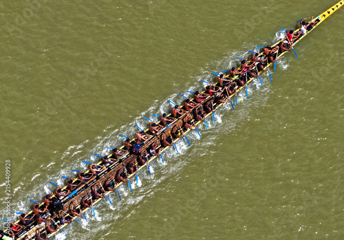 Aerial view of a traditional long boat with numerous rowers paddling in unison across the river in Sirajganj, Rajshahi Division, Bangladesh.