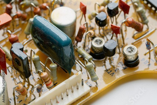 Close-up of a vintage circuit board with various colorful resistors and capacitors. Retro electronic hardware architecture. Detailed internal view of an analog device.	
