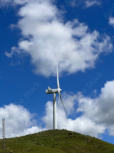 Wind turbine on green hillside under blue sky