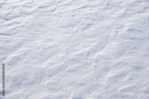 Snow texture with wind patterns, white winter background, fresh snowy surface with soft shadows and ice crystals