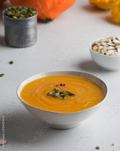 Creamy pumpkin soup with seeds on light table