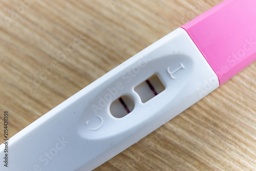 Фотография Macro shot of a rapid pregnancy test stick with a positive result indicating two lines in indicators, selective focus
