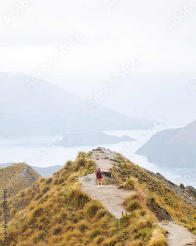 Female hiker on Roys Peak summit trail with Lake Wanaka, New Zealand