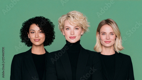 Corporate Team Concept with Three Businesswomen in Black Blazers on Green Studio Background