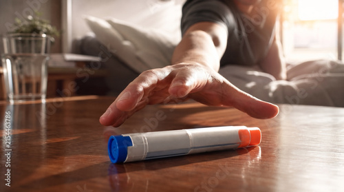 Hand Reaching For Epinephrine Auto-Injector On Wooden Nightstand During Medical Emergency, Life Saving Allergy Treatment Medication