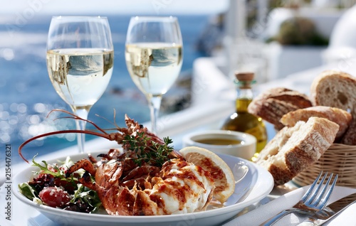 luxury grilled lobster with fresh salad, white wine, artisan bread and olive oil served at a sunlit mediterranean seaside restaurant