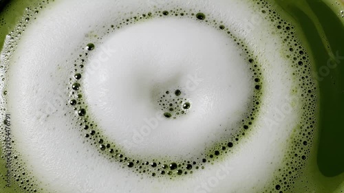 Macro splash of green liquid with white foam bubbles.