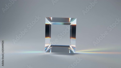 Glass block sits centered on a clean studio surface refracting crisp white light into subtle prismatic rainbows across the minimal background.