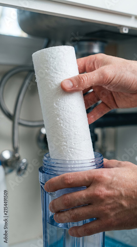 Inserting white replacement water filter into purification cylinder unit