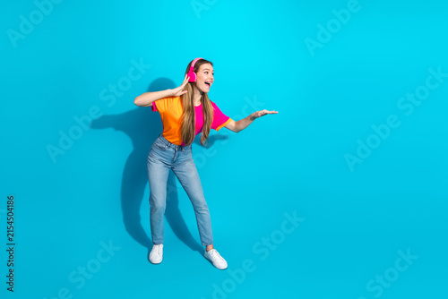 Obraz na płótnie Young woman dancing with headphones on bright blue background lifestyle fashion