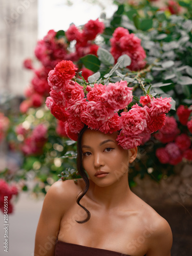 Asian Woman Standing Under Blooming Pink Roses Wall