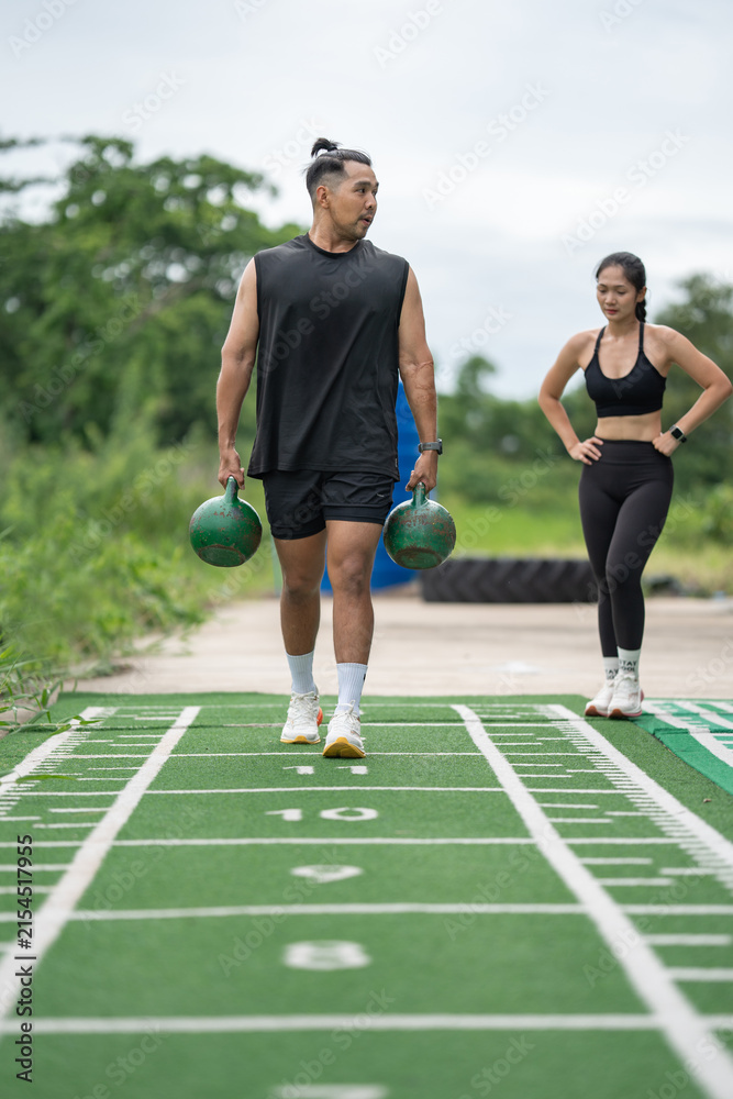 Obraz premium Asia man carrying kettlebells on running track