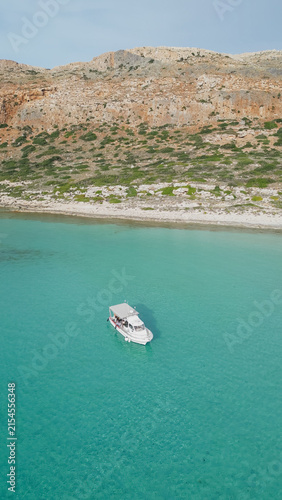 Photography Vertical drone aerial view of small pleasure boat anchored in crystal clear turq