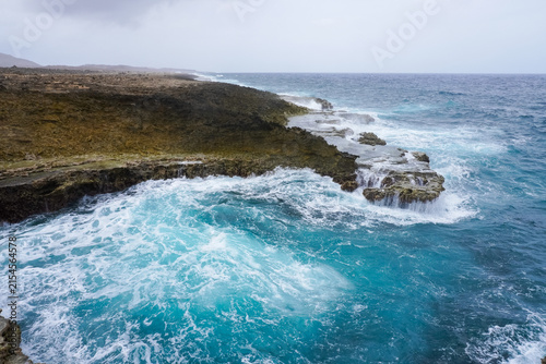 Cuadro en lienzo Turquoise ocean water foaming and swirling against dark rocky coral cliffs in Curaçao