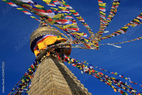 Boudhanath Stupa decorated with colorful Buddhist prayer flags against a deep blue sky in Kathmandu, Nepal