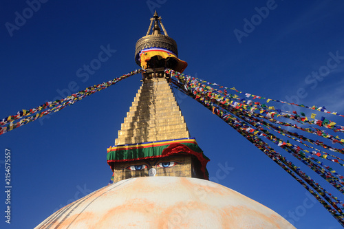 Boudhanath Stupa decorated with colorful Buddhist prayer flags against a deep blue sky in Kathmandu, Nepal