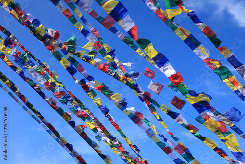 Colorful Tibetan Buddhist prayer flags fluttering against a clear blue sky, symbolizing peace, compassion, spirituality and Buddhist tradition