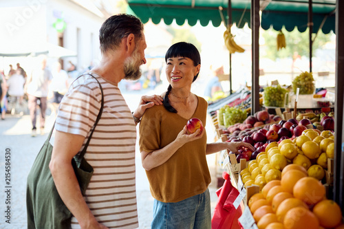 Couple Shopping at Outdoor Farmers Market — Asian Woman Holding Apple and Smiling With Partner